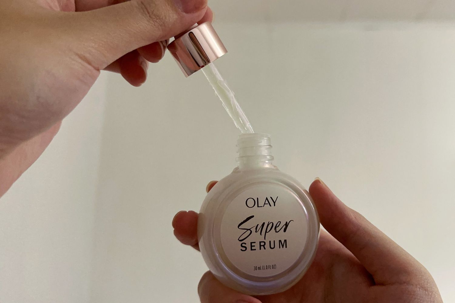 A hand lifting the applicator out of the Olay Super Serum bottle