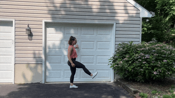 trainer doing leg swings outside in front of garage