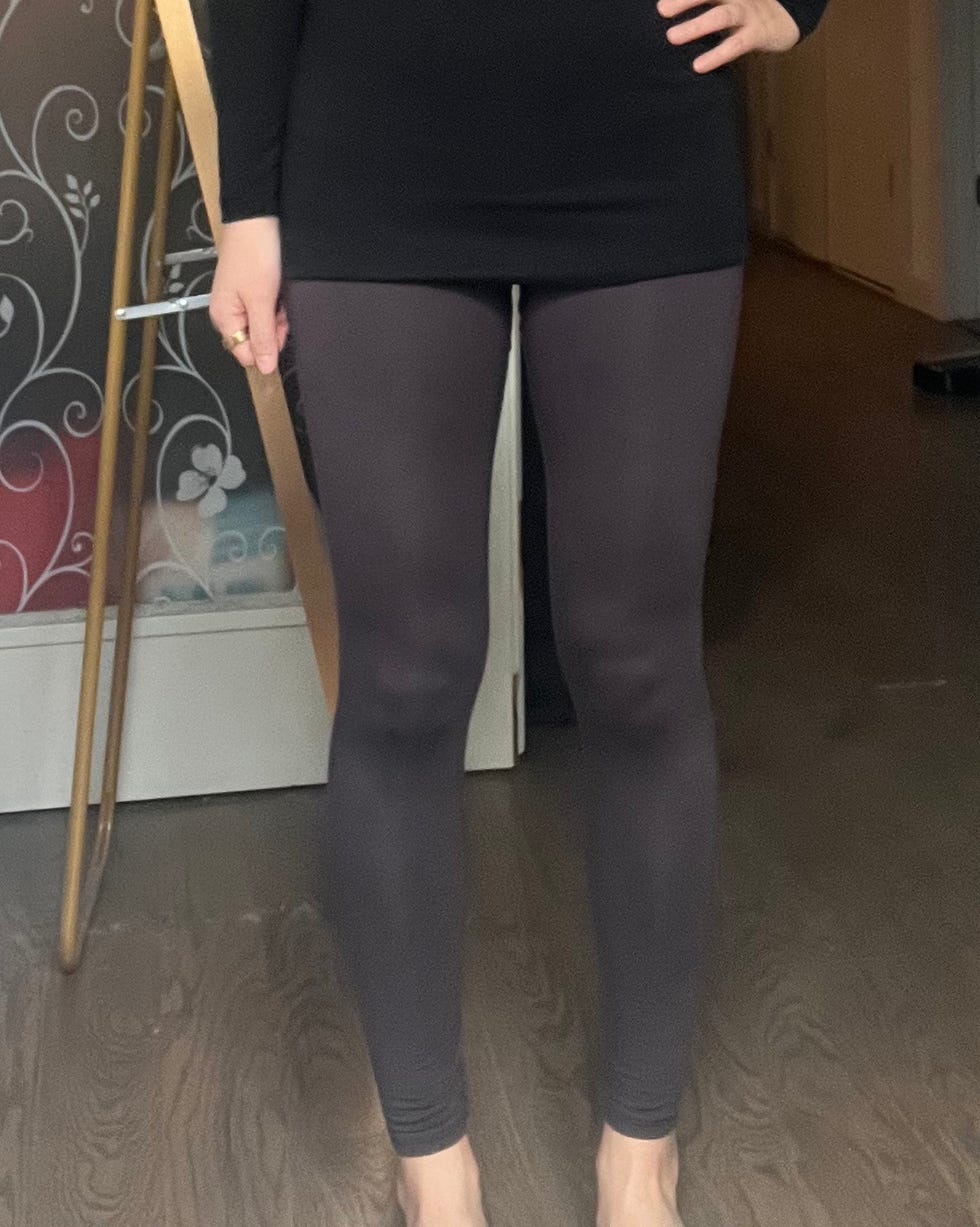 person wearing a black top and dark leggings standing indoors