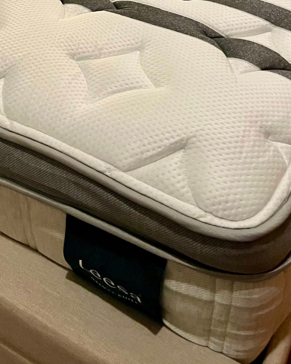 mattress on a bed with a headboard and bedside lamp