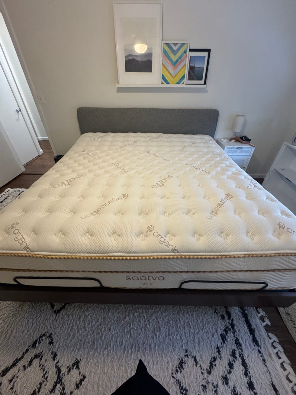 A bed with a Saatva mattress in a well-lit bedroom.