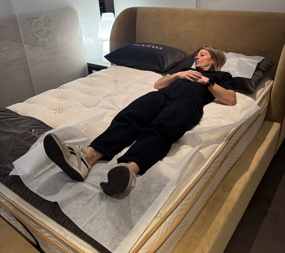 Person lying on a mattress in a store.