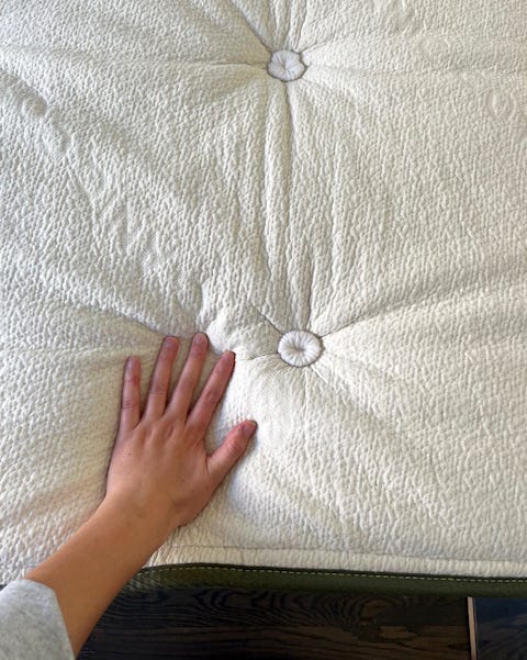 a hand resting on a textured tufted fabric surface
