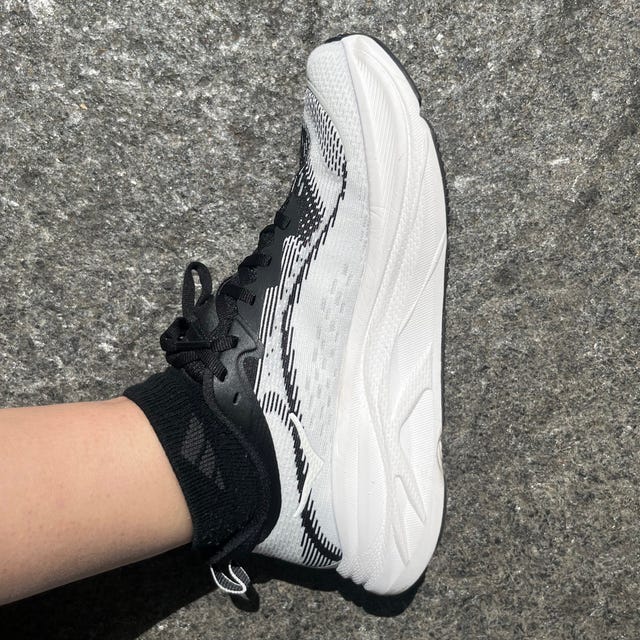 Close-up of a black and white athletic shoe on a textured surface.