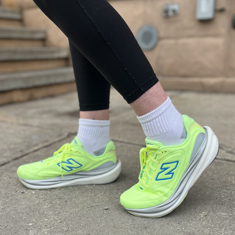 Footwear worn with leggings on a sidewalk near steps.