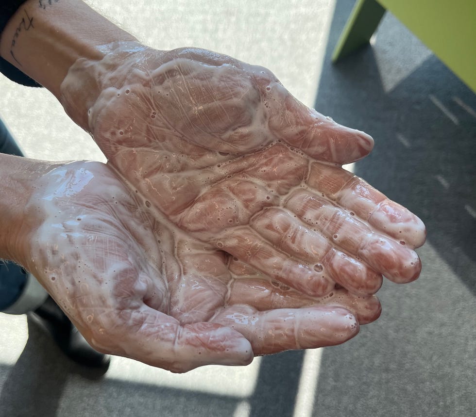 Hands covered in soapy substance with a shadowy background.