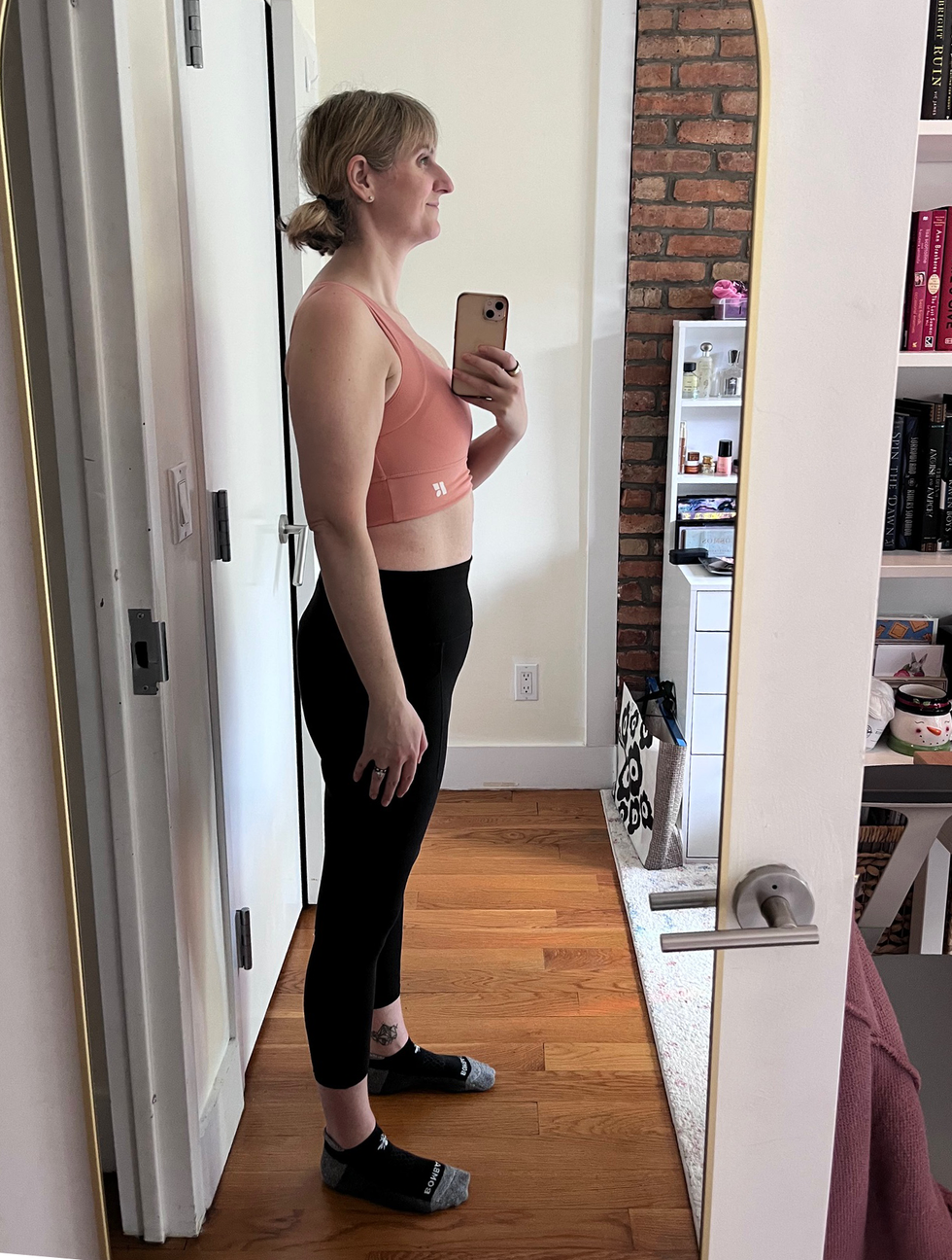 Side profile of a person in activewear standing in front of a mirror.