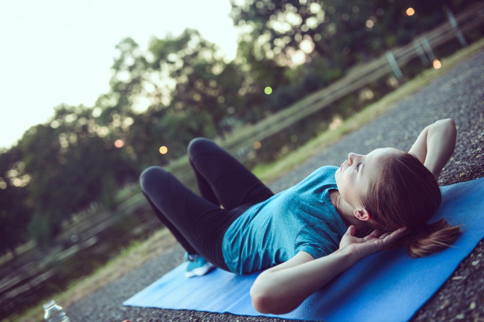 Young Female Athlete Performs Abs Crunches in City Park Young Female Athlete Performs Abs Crunches in City Park
