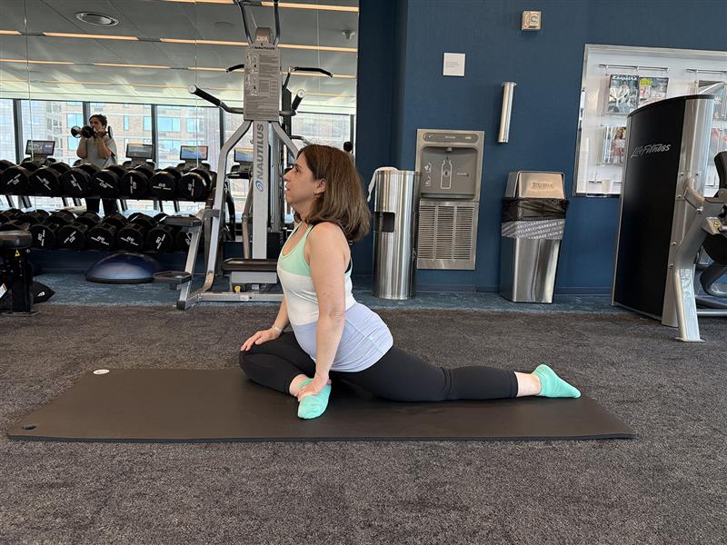 Woman performing a yoga pose in a gym setting.