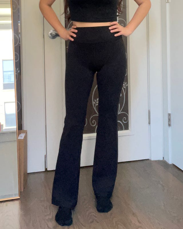 Person wearing a black crop top and black leggings in front of a closed door.