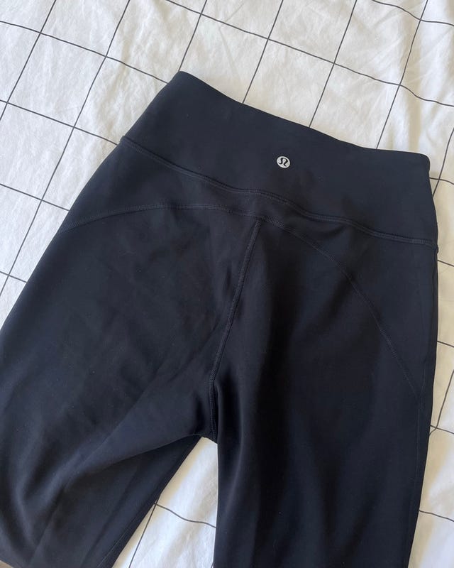 Black athletic shorts with logo on grid-patterned fabric background.