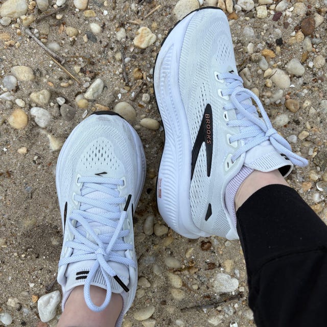 White Brooks sneakers on sandy, pebbled ground.