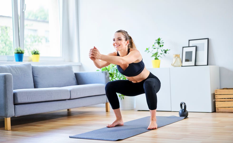 smiling woman doing squats during home workout