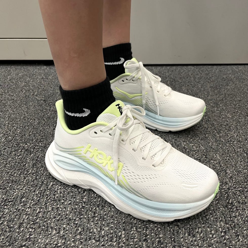 White athletic shoes with lime green accents worn with black socks.