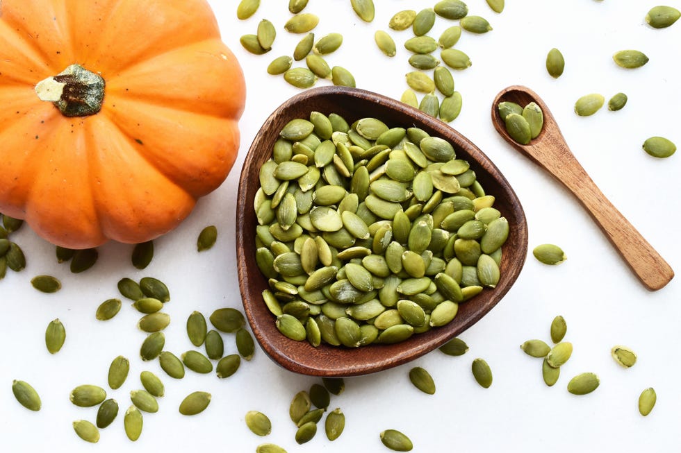 pumpkin seeds in a wooden bowl on a white table