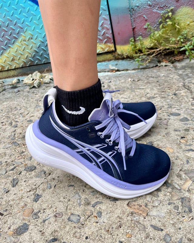 Close-up of a person's foot wearing dark blue athletic shoes and black socks against a colorful urban background.