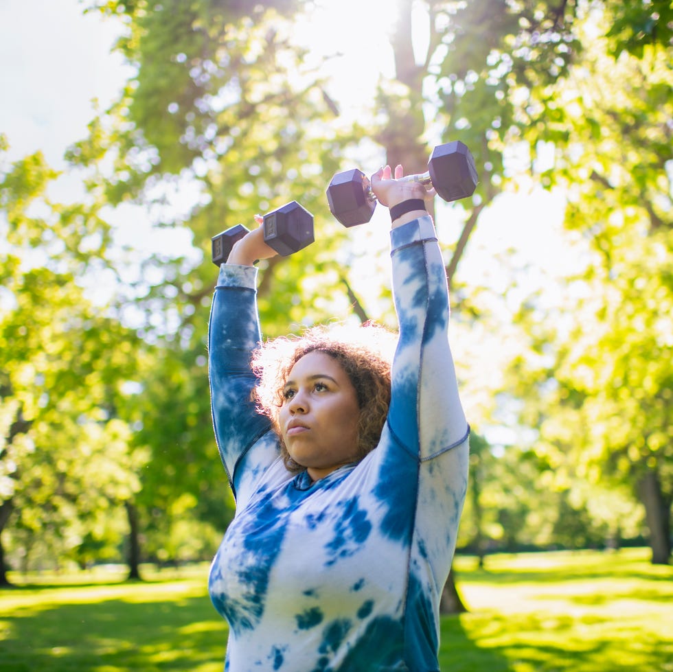 Young woman working out with hand weights outdoors