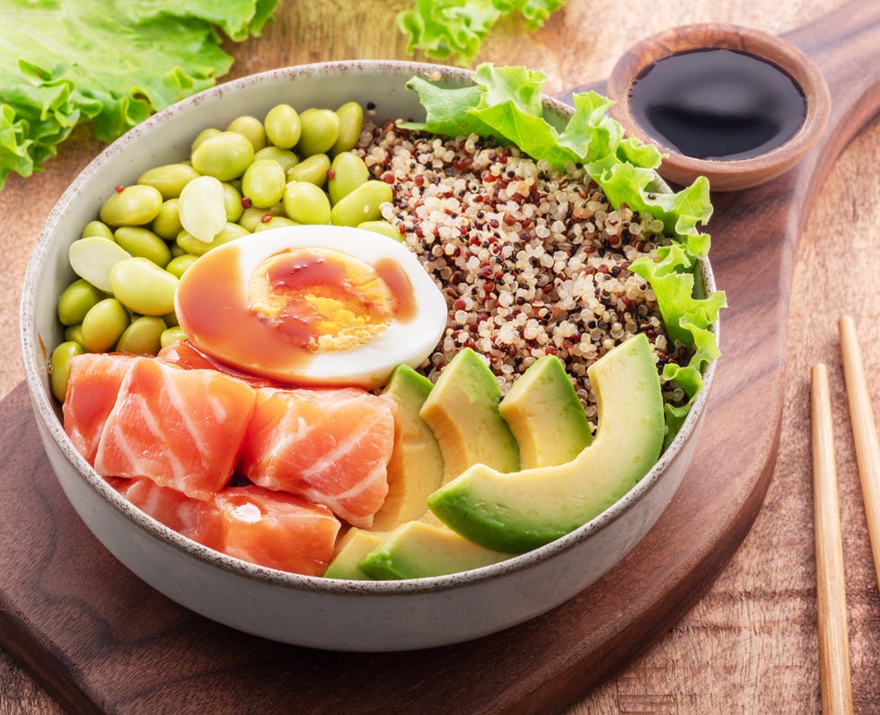 salmon quinoa bowl with greens and vegetable on the wooden table balance in bowl top view
