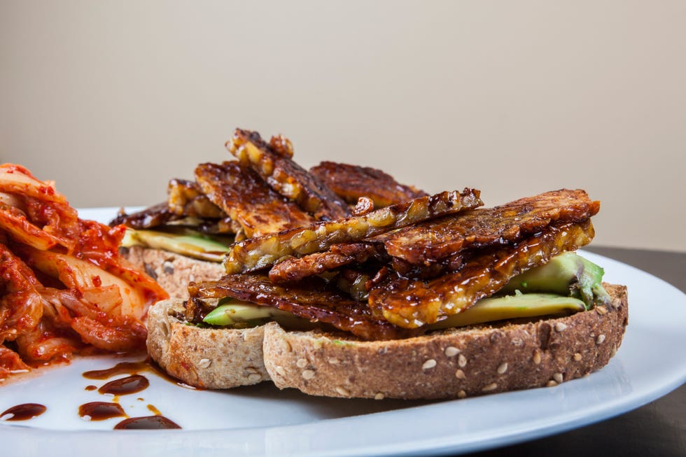 vegan food with grilled tempeh, black garlic, avocado, toast and kimchi