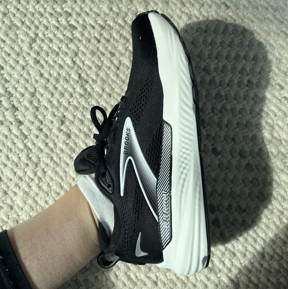 Black and white running shoe from Brooks on a textured surface.