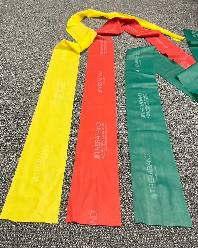 Stretch bands in yellow, red, and green colors laid out on a textured surface.