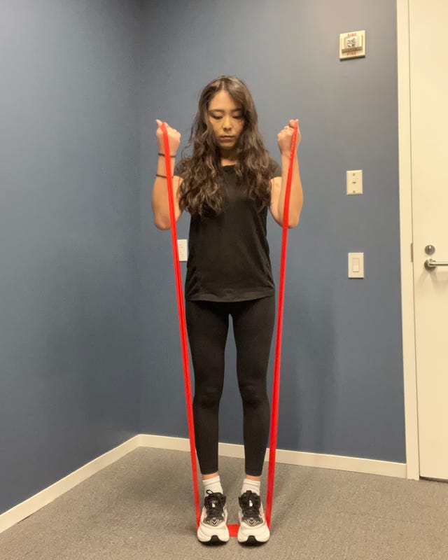 Person performing an exercise with red resistance bands in a fitness studio.