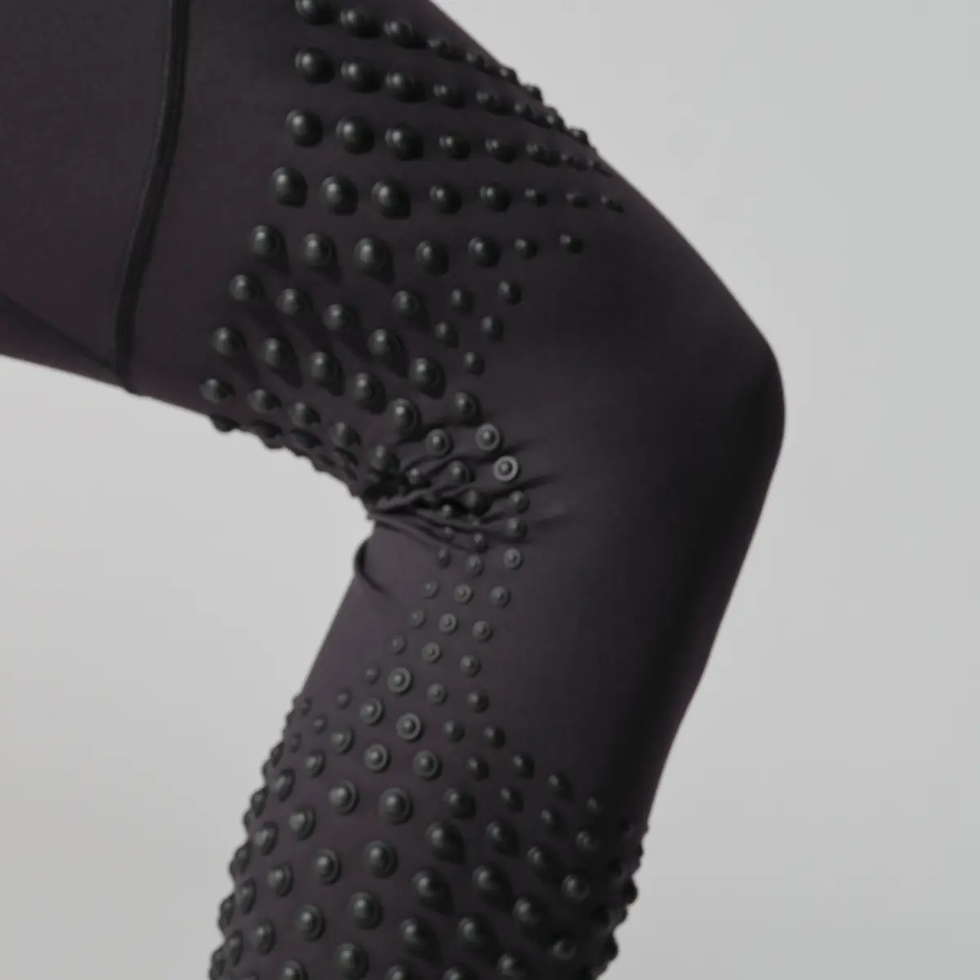 Close-up of textured athletic leggings with raised dots on the knee area.