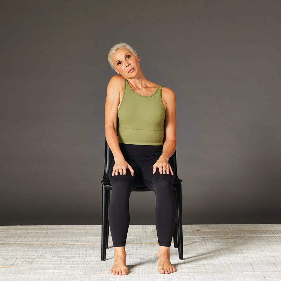 woman doing an ear and shoulder tap stretch in a chair