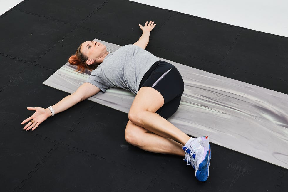 A person performing a twisted stretch on a mat during a fitness workout.