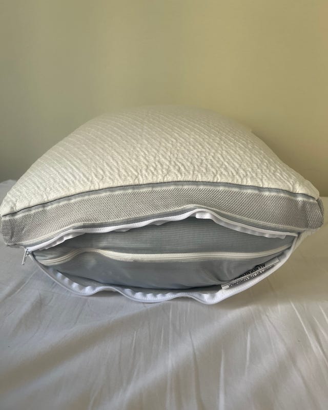 White pillow with a textured surface and visible zipper on a soft bedspread.
