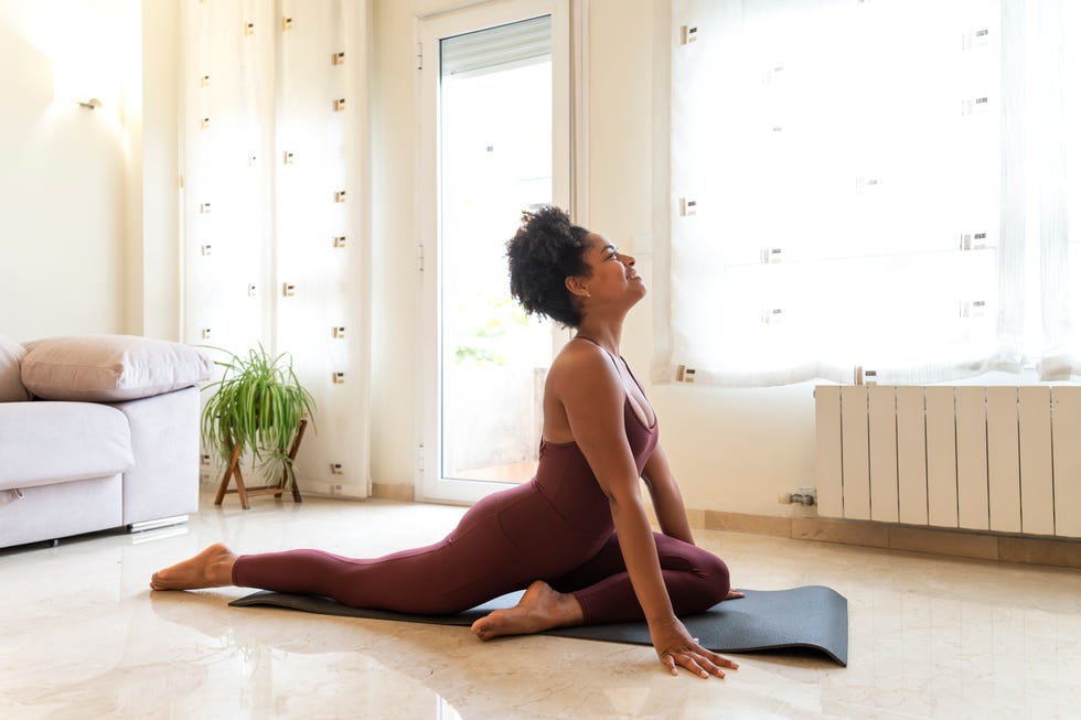 sciatica stretches pain relief - Young woman practicing yoga pigeon pose at home