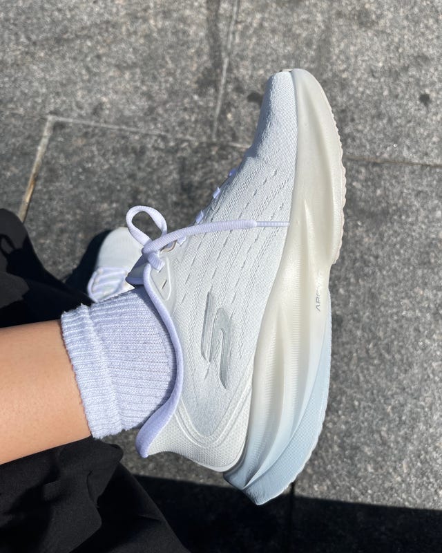 White sneaker with light blue accents and white socks on a stone surface. White sneaker with light blue accents and white socks on a stone surface.