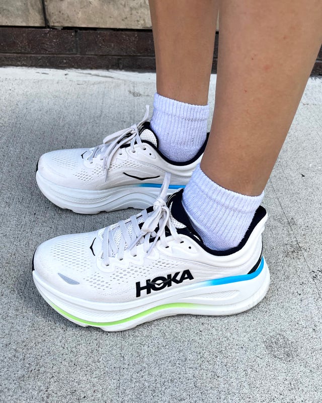 White athletic shoes with colorful accents worn with white socks on a concrete surface.
