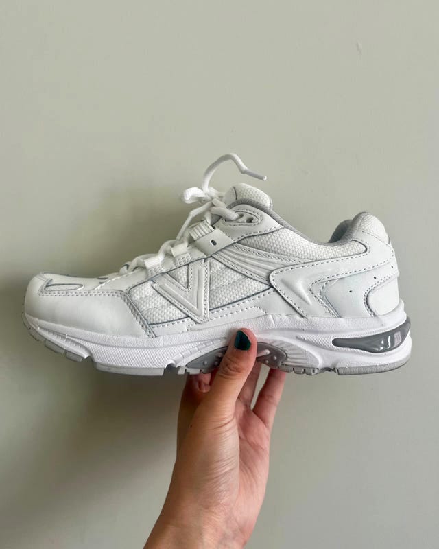 White athletic shoe held in hand against a light background.