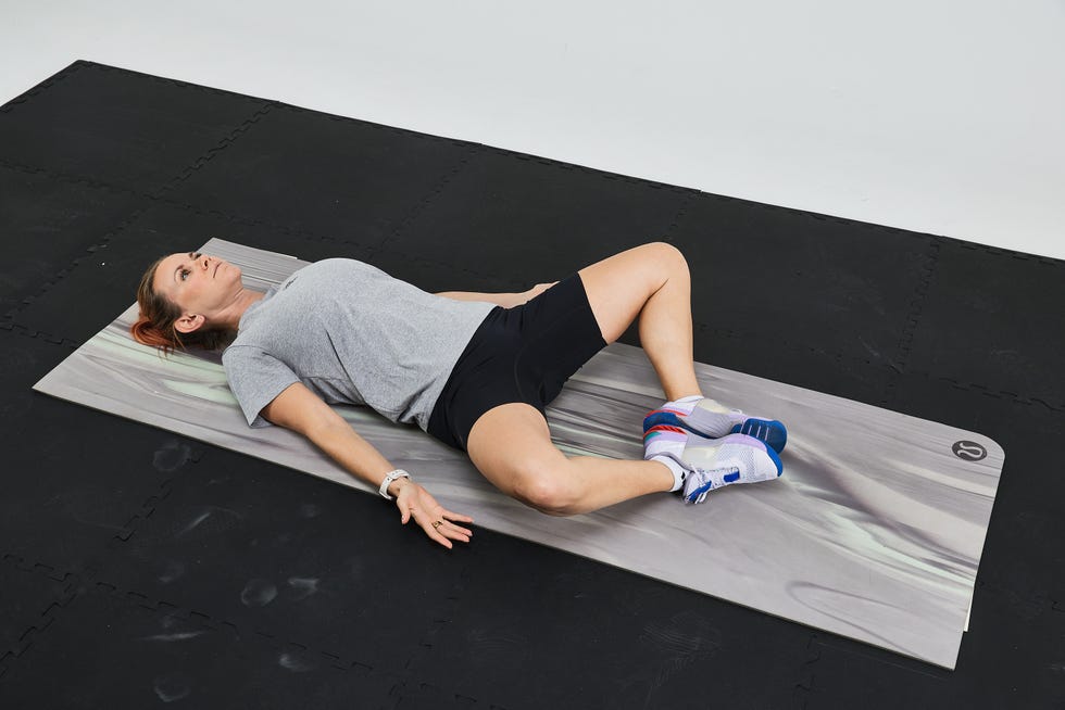Person performing a stretching exercise on a yoga mat in a fitness environment.