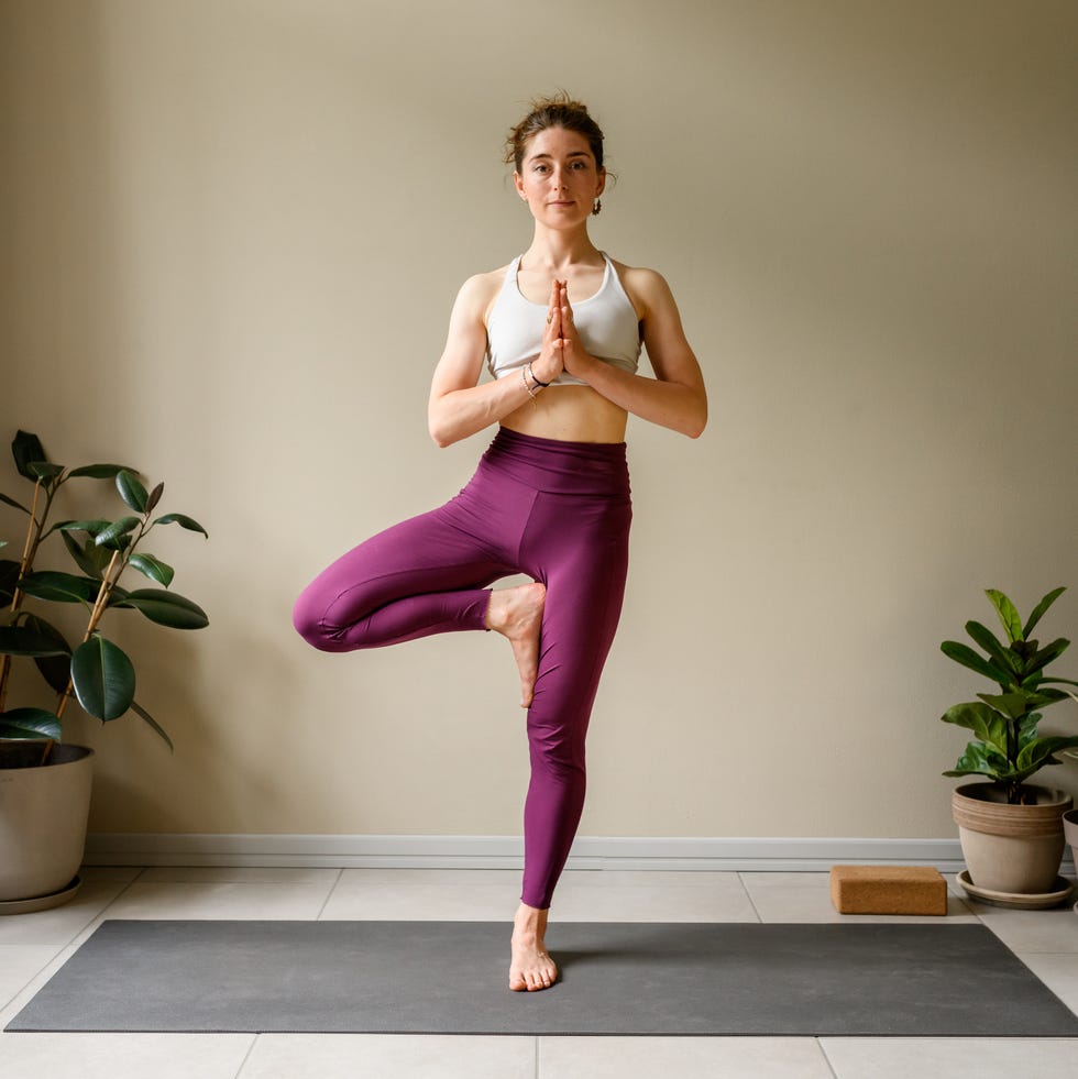 Professional woman practicing yoga at home: Tree, Vrikshasana
