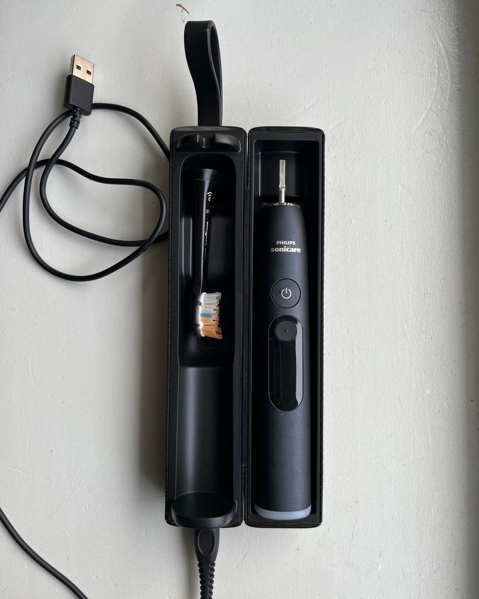 Black electric toothbrush and charging case with USB cable, featuring a brush head and control button.