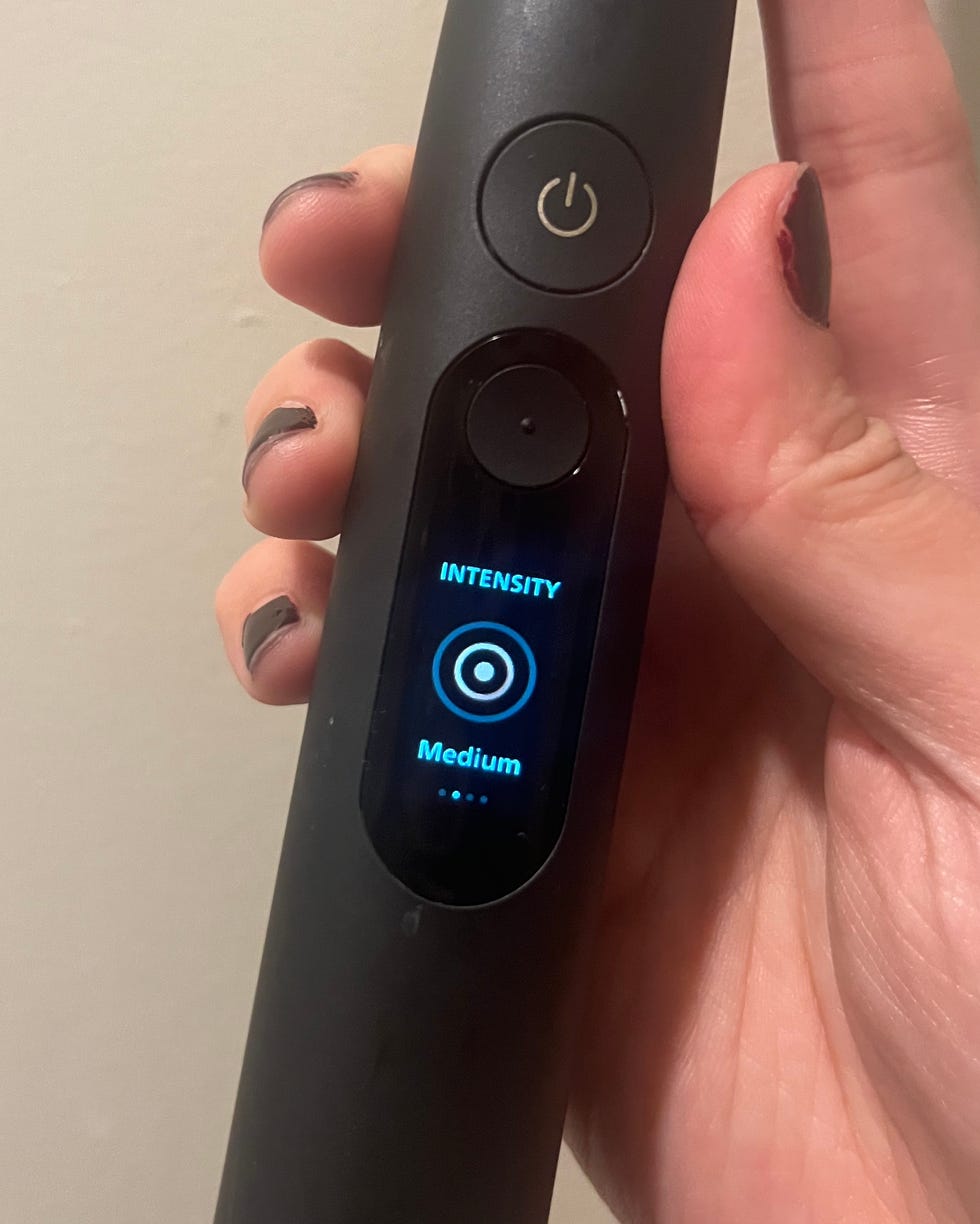 Philips Sonicare electric toothbrush with a display showing medium intensity setting.