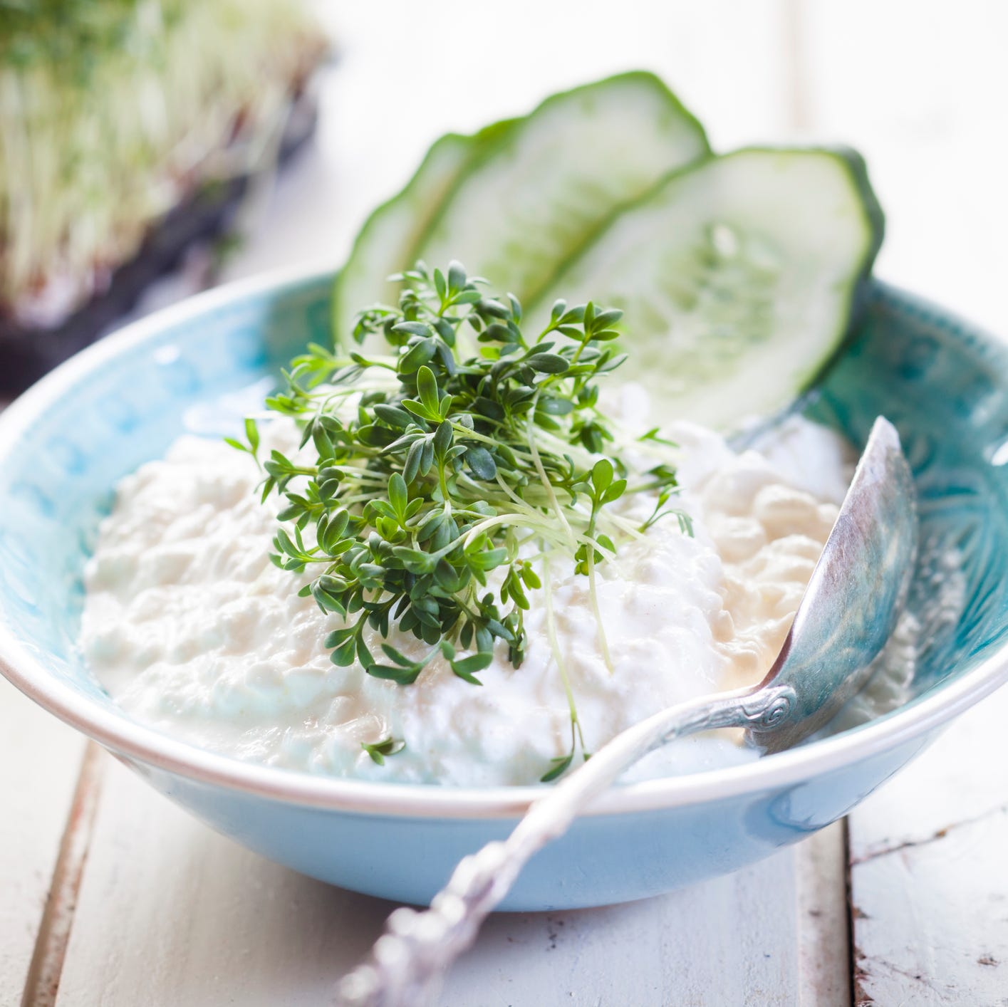 Bowl of cottage cheese with cress and cucumber slices Bowl of cottage cheese with cress and cucumber slices