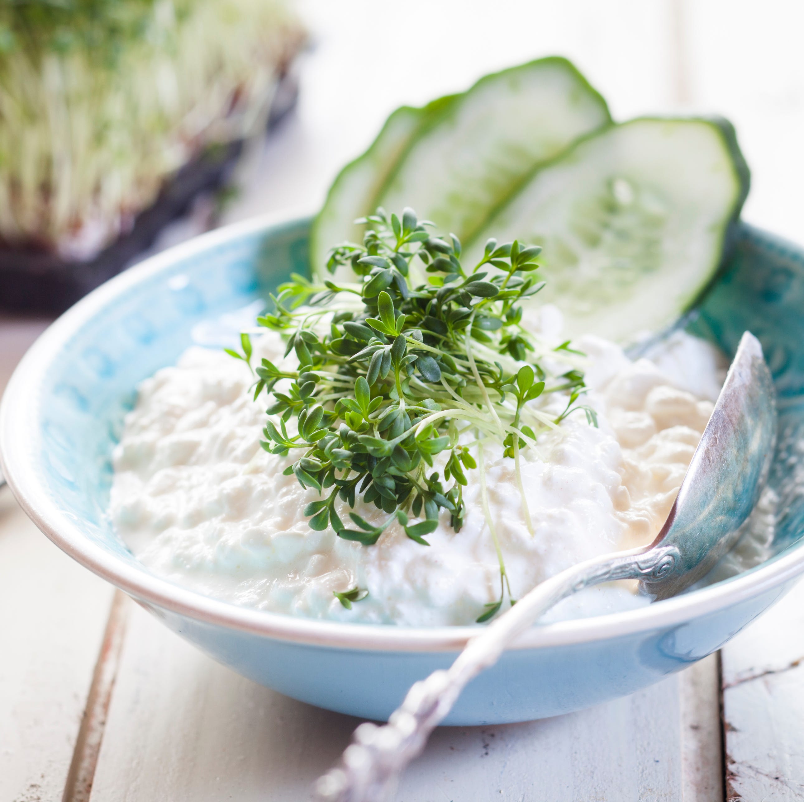 Bowl of cottage cheese with cress and cucumber slices