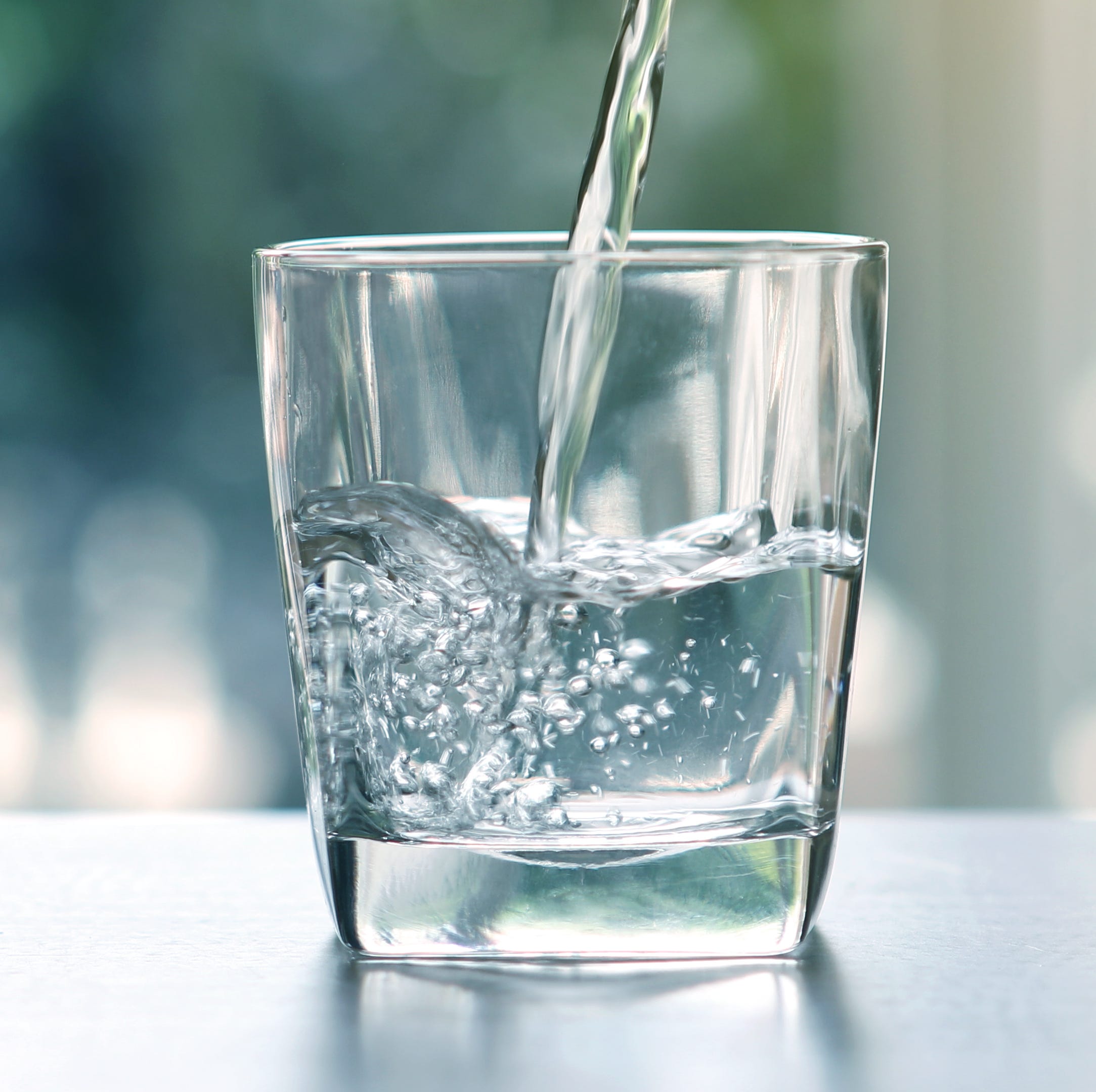 Close up the  pouring purified fresh drink water from the bottle on table in living room