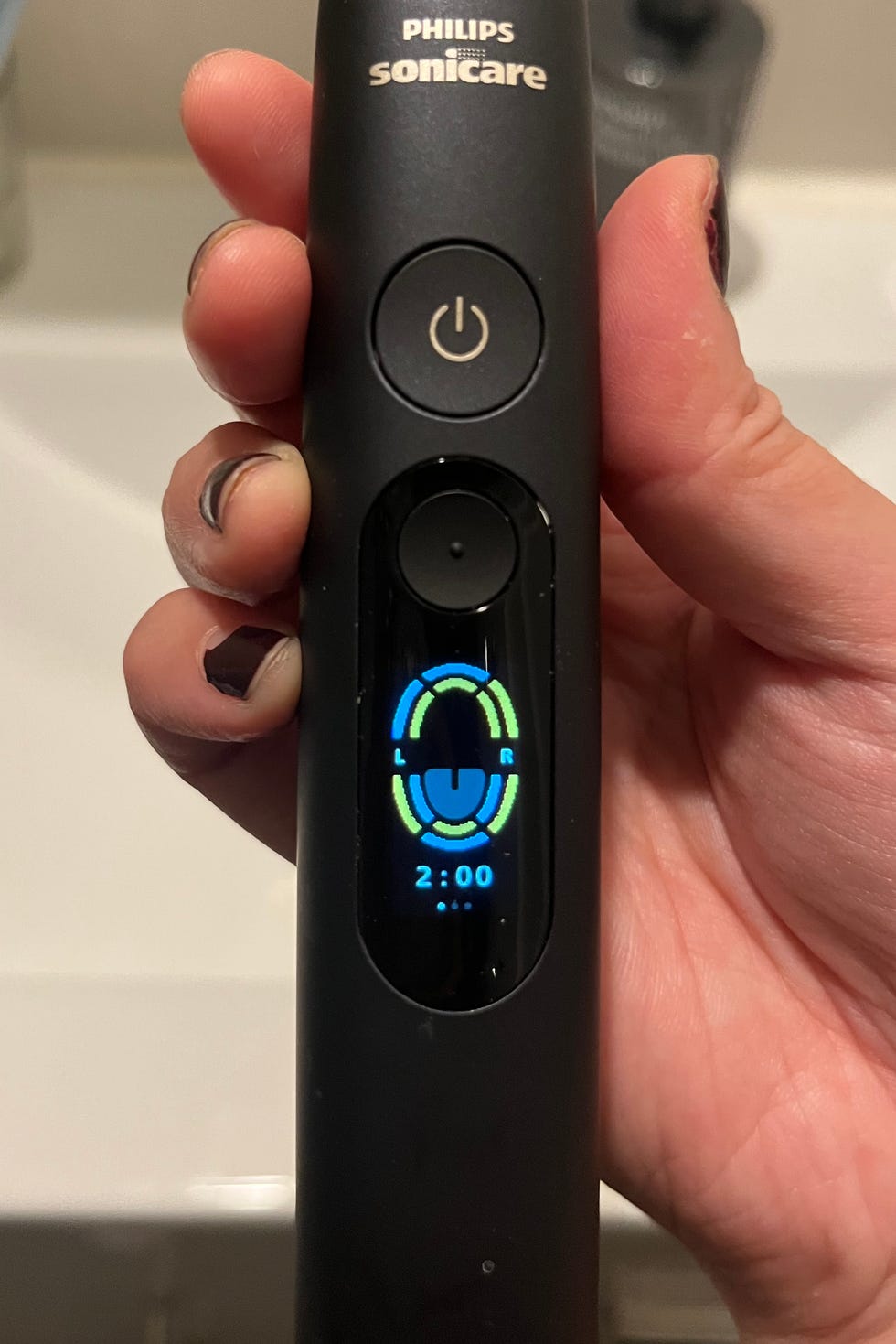 Philips Sonicare electric toothbrush displaying timer and brush head indicator in a bathroom setting.