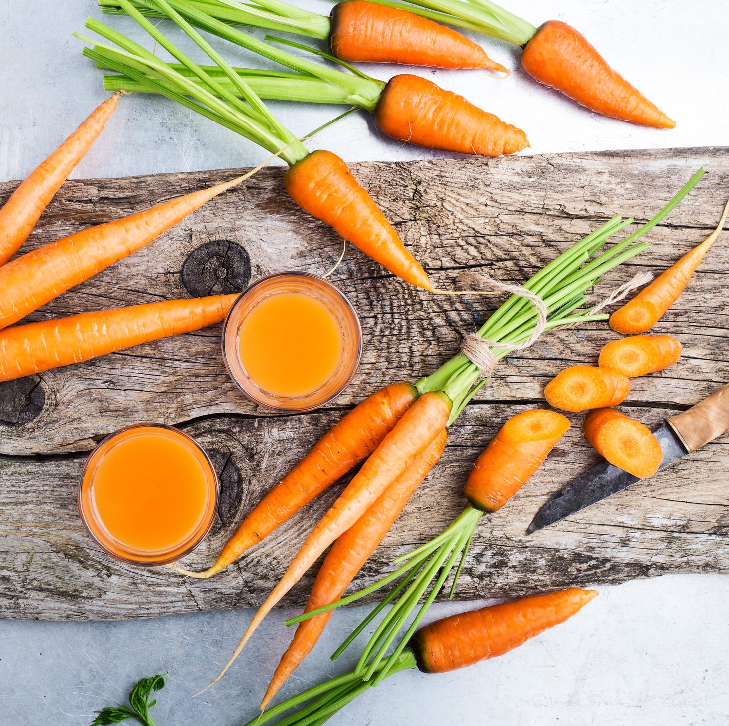 Fresh carrot juice and raw organic vegetables over rustic wooden table Fresh carrot juice and raw organic vegetables over rustic wooden table