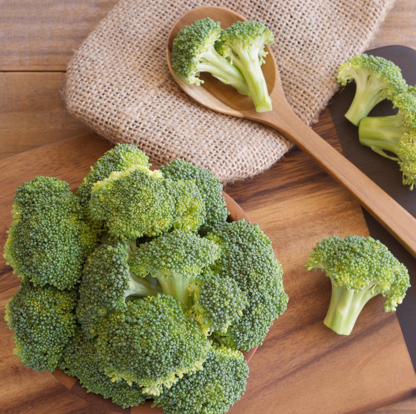 High Angle View Of Broccoli With Spoon And Burlap On Cutting Board At Table High Angle View Of Broccoli With Spoon And Burlap On Cutting Board At Table