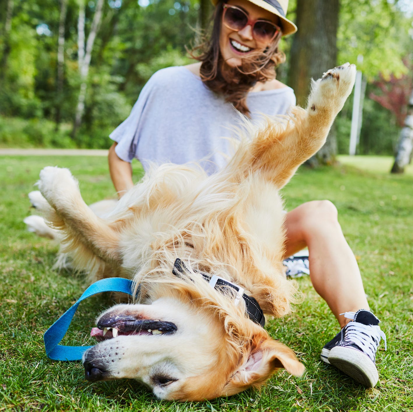 Joyful young woman playing with her dog outdoors in the park