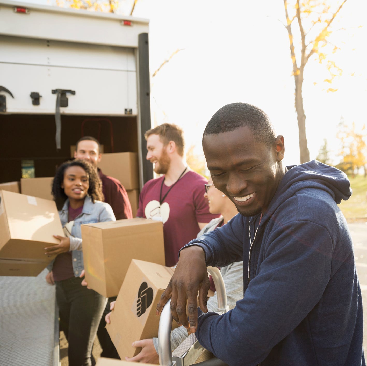Smiling volunteers unloading cardboard boxes from truck